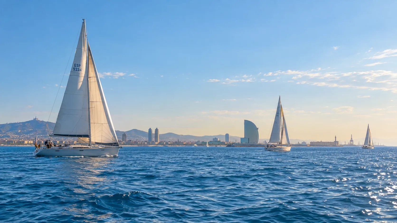 Veleros cruzando la bahía frente a Barcelona, con el perfil de la ciudad bajo en el horizonte